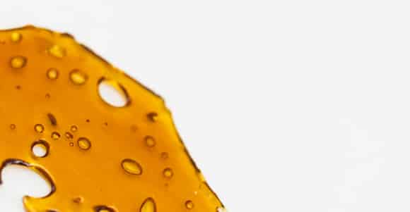 chronic store cannabis shatter close up photo orange processed shatter with holes in it